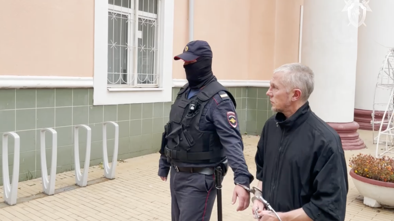 Мужчина, обвиненный в изнасилованиях и убийствах девушек 20-летней давности, в сопровождении сотрудника полиции